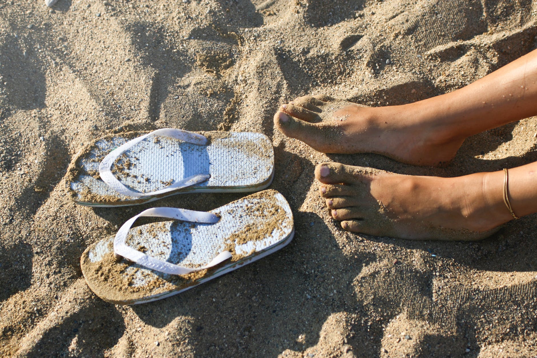 photography of a girl s feet near flip flops